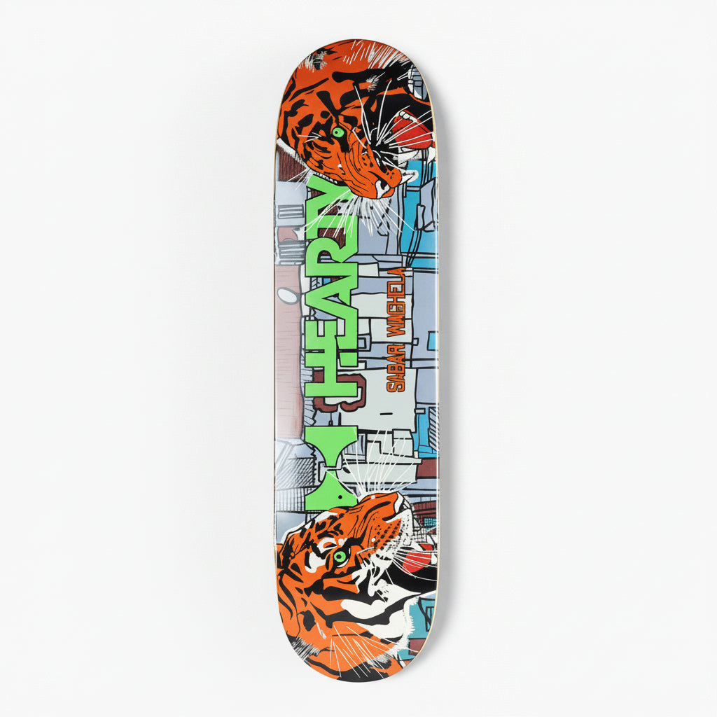 A skateboard deck featuring a bold comic-style graphic design with two orange and black tiger illustrations at the top and bottom, a gray cityscape background, and large green vertical text reading 'M. HEAVEN' with smaller text 'SHAR VASEY' beside it, shown on a light gray background.