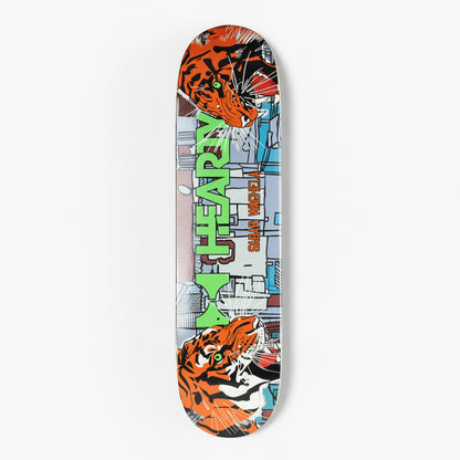 A skateboard deck featuring a bold comic-style graphic design with two orange and black tiger illustrations at the top and bottom, a gray cityscape background, and large green vertical text reading 'M. HEAVEN' with smaller text 'SHAR VASEY' beside it, shown on a light gray background.